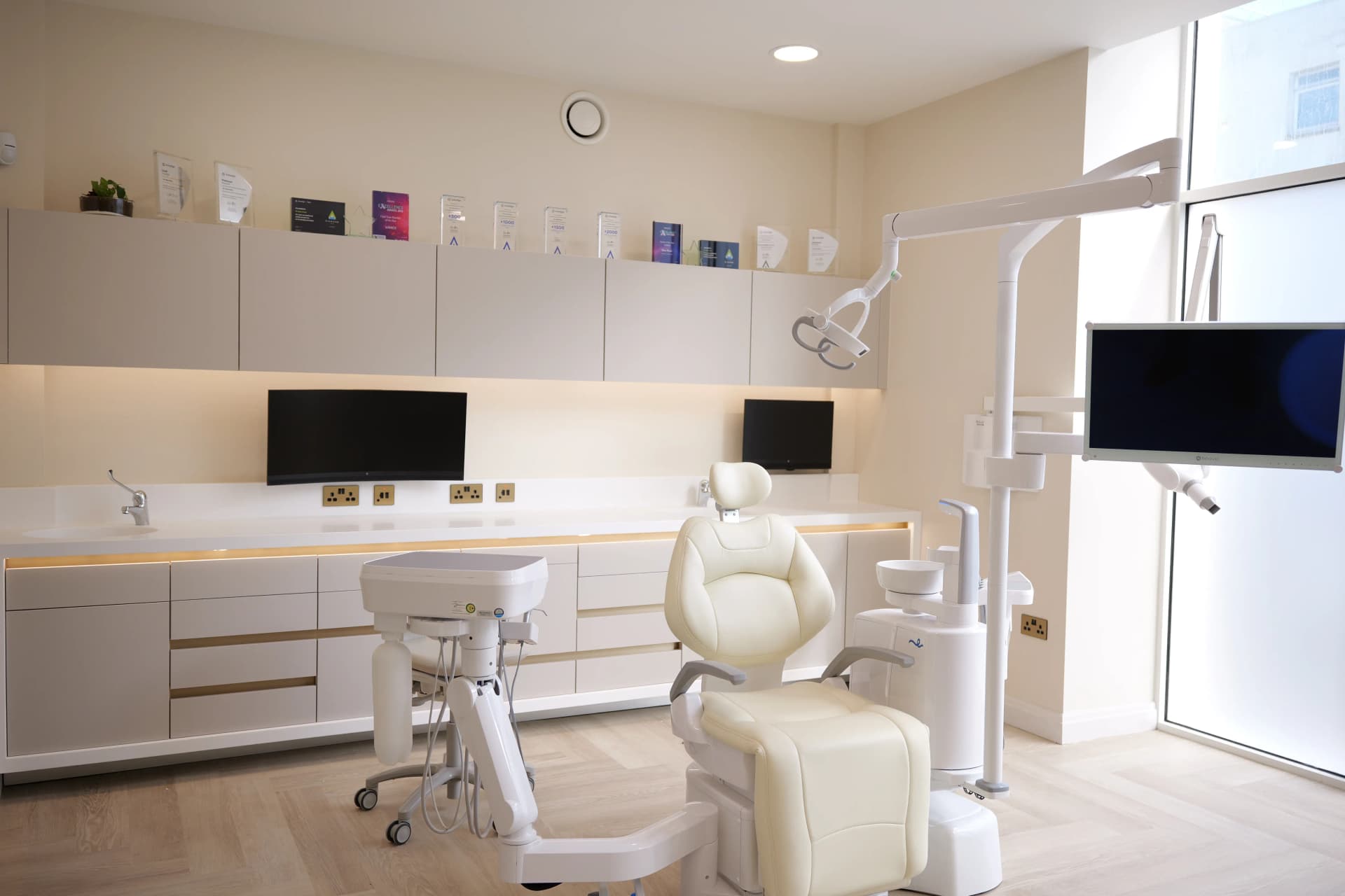 odern dental clinic with a dental chair, monitors, and sleek cabinetry